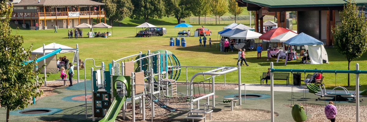 Children playing on playground near event tents in LeBourdais Park