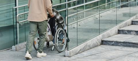 Man pushing a person in a wheelchair up a ramp